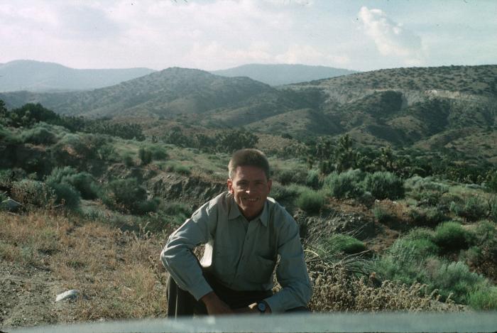 Photographic Materials, Research materials depicts: Man with short cropped hair kneeling in the brush overlooking the landscape of Area 51