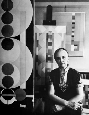 Posters depicts: black and white photo of elegant gray haired woman in front of geometric art